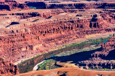 View from Grand View Point showing Green River bending through steep red rock canyon walls and stratified desert terrain in Canyonlands National Park Utah