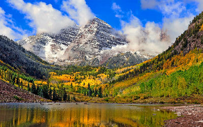 Maroon Bells peaks above autumn aspens reflected in a lake near Aspen, Colorado.