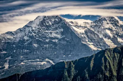 Close view of the Eiger and Mönch peaks with snow-covered rock faces and cloud band above, Bernese Alps, Switzerland.