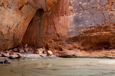 Shallow water and fallen rocks beneath the towering red sandstone walls of Cathedral Gorge in Purnululu National Park.