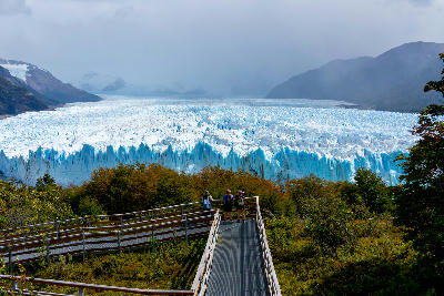 Tourists standing on Perito Moreno boardwalk viewing platform overlooking the glacier in Patagonia, Argentina.