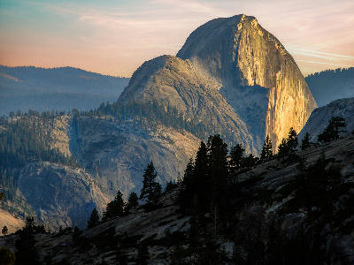 Back side of Half Dome at sunset from Olmsted Point with granite slopes and forest in Yosemite National Park.
