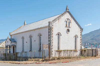Historic 1913 synagogue building in Ladismith with whitewashed walls, arched windows, and mountain scenery in the background, Klein Karoo, Western Cape, South Africa.