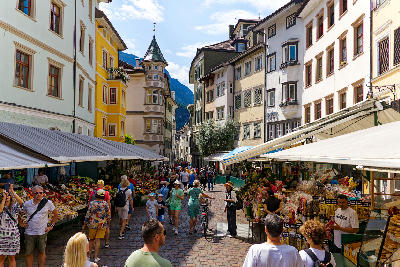 Street market with pedestrians and colourful buildings in Bolzano old town, South Tyrol, Italy.