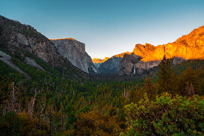Tunnel View Yosemite Valley California showing El Capitan, Bridalveil Fall and Cathedral Rocks in sunset light above forested valley.