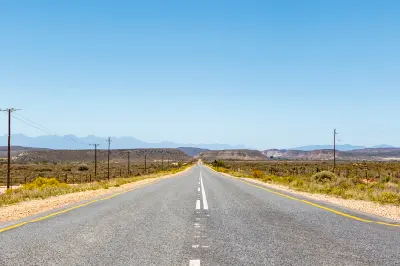Route 62 highway running through open semi-arid Karoo plains with distant mountain ranges in the Western Cape of South Africa.