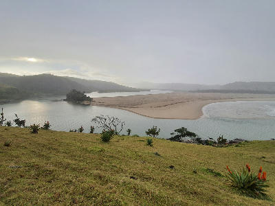 Mthatha River Mouth with estuary channel, sandbar and ocean shoreline viewed from a grassy hillside on the Wild Coast.