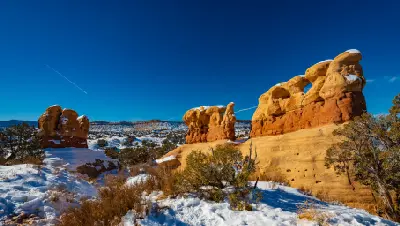Sculpted sandstone hoodoos dusted with winter snow at Devil’s Garden beneath a deep blue sky.