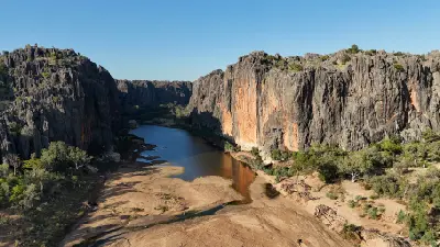 Aerial view of the Lennard River winding between the towering limestone walls and sandy riverbed of Bandilngan (Windjana Gorge).
