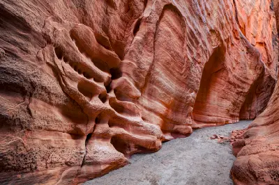 Eroded red sandstone walls with sweeping patterns and rounded alcoves line the sandy passage through Dry Fork Narrows.
