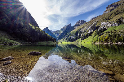 Clear alpine lake with rocky foreground and reflections of peaks in Appenzell, Switzerland.