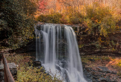 Long exposure photograph of Dry Falls flowing over a rock cliff surrounded by autumn forest in the Blue Ridge Mountains of North Carolina.