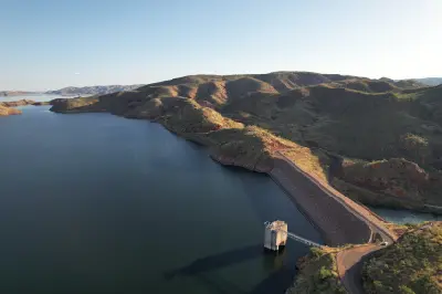 Aerial view of the Lake Argyle dam wall and intake tower surrounded by the vast reservoir and rugged Kimberley hills.