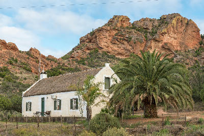 Traditional farmhouse beneath red sandstone hills at Red Stone Hills in the Klein Karoo of South Africa’s Western Cape