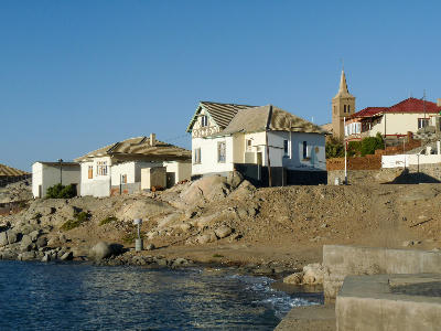 Historic waterfront buildings and church tower in Lüderitz, Namibia, overlooking the Atlantic coastline.