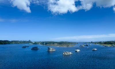Houseboats and boats anchored on the calm waters of the Knysna Lagoon under a blue sky on South Africa's Garden Route.