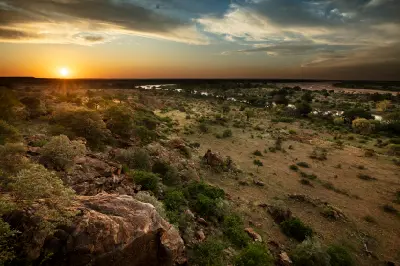 Sunset view from a rocky hillside overlooking the confluence of the Limpopo and Shashe rivers, with riverine woodland and open savanna stretching across the Mapungubwe landscape in Limpopo, South Africa.