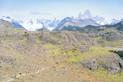 Hiking trail to Mirador de los Cóndores with people walking toward a viewpoint and Fitz Roy peaks in the distance, Patagonia, Argentina.