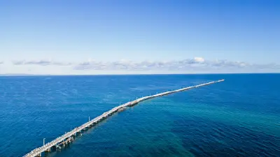 Aerial view of the long Busselton Jetty stretching across the turquoise waters of Geographe Bay.