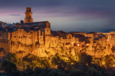 Twilight view of the hilltop town of Pitigliano illuminated on volcanic cliffs in the Maremma region of Tuscany, Italy.