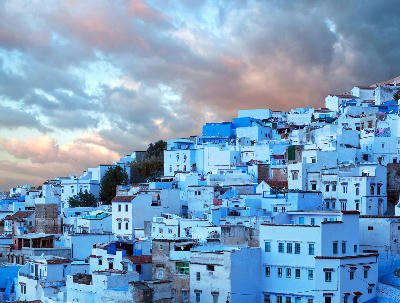 Blue-painted medina buildings of Chefchaouen beneath dramatic clouds in the Rif Mountains of Morocco