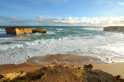 Wide coastal view of London Arch and surf in Port Campbell National Park, Victoria.