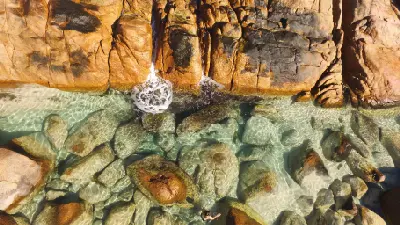 Overhead aerial view of clear water and granite boulders at Injidup Natural Spa, Western Australia.