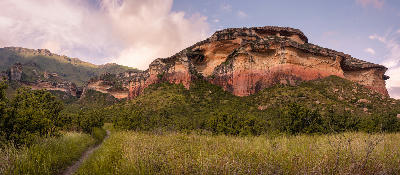 Mushroom Rock sandstone formation rising above grassland and mountain slopes near Clarens in the eastern Free State, with dramatic layered cliffs and surrounding highland scenery.
