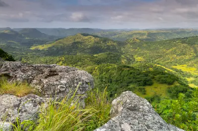Rocky viewpoint overlooking green valleys, wooded hills and layered ridgelines in the Valley of a Thousand Hills region of KwaZulu-Natal.