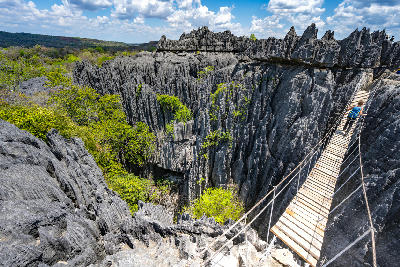 Backpacker crossing a suspension bridge above the limestone pinnacles of Tsingy de Bemaraha National Park in Madagascar