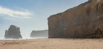 Beach beneath towering limestone cliffs and sea stacks at Gibson Steps, Great Ocean Road, Victoria, Australia.