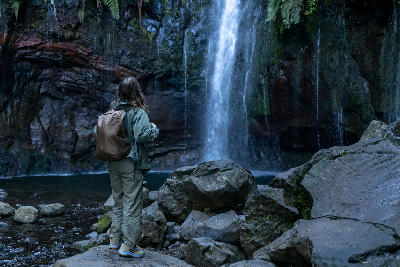 Hiker looking at waterfalls flowing into the lagoon at 25 Fontes in the Rabaçal valley on Madeira Island, Portugal.
