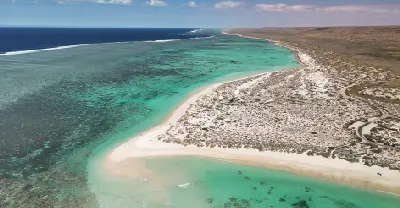 Aerial view of Turquoise Bay with white sand, turquoise lagoon and Ningaloo Reef extending along the coast.