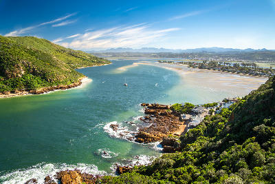 Aerial view of the Knysna Heads and estuary entrance, where a narrow channel between rugged coastal headlands opens into the expansive Knysna Lagoon along South Africa's Garden Route.