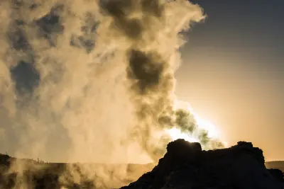 Castle Geyser silhouette with steam plume at sunrise Yellowstone