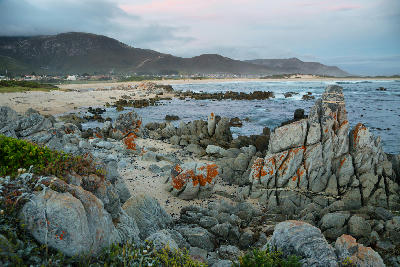 Rocky shoreline and ocean waves at Kleinmond beneath the coastal mountains of the Overberg region in South Africa.