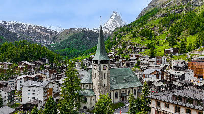 Zermatt village centered on St. Mauritius Church with traditional chalets and the Matterhorn rising in the background, Swiss Alps.