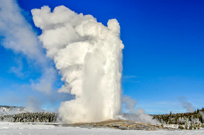 Old Faithful geyser eruption winter Yellowstone National Park Wyoming snow steam plume blue sky