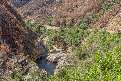Rocky river gorge and burnt mountain slopes inside Tradouw Pass between Barrydale and Swellendam in the Western Cape, South Africa.