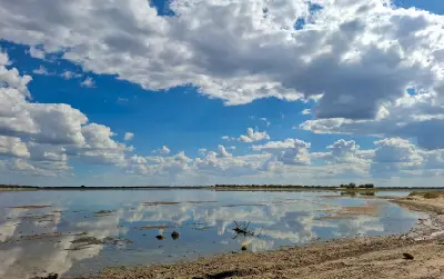 Cloud-filled sky reflected in a flooded seasonal pan after the rainy season in Nxai Pan National Park, Botswana.