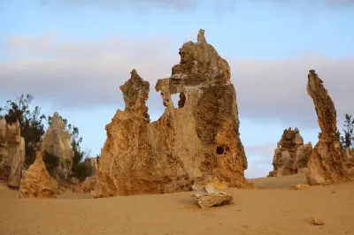 Close view of a sculpted limestone pinnacle rising from the sandy desert.