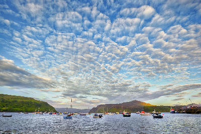 View over Portree Bay on the Isle of Skye before sunset, with the harbour, colourful houses, and soft evening