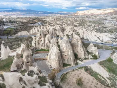 Aerial view of the Paşabağ Fairy Chimneys in Cappadocia, Turkey, showing mushroom-shaped rock formations, cave dwellings, and the surrounding volcanic landscape.