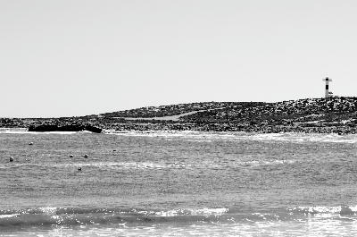 View across the bay at Hondeklip Bay toward the coastal lighthouse and rocky shoreline on South Africa's remote Namaqualand coast.