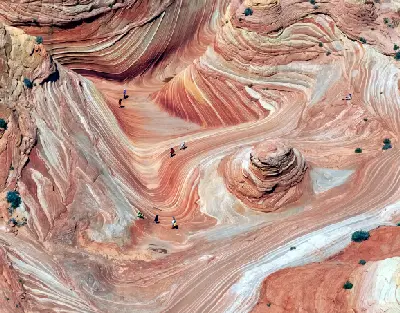 Aerial view of The Wave with layered sandstone patterns and hikers for scale in Coyote Buttes North Arizona