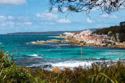 Turquoise coastal water and orange lichen-covered granite rocks at The Gardens, Bay of Fires, Tasmania.