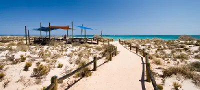 Sandy beach access path and shaded picnic area overlooking the turquoise waters of Turquoise Bay.