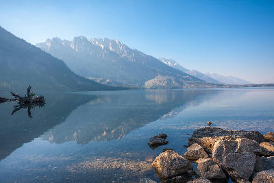 Calm Jenny Lake with rocky shoreline and reflections of the Teton Range, Grand Teton National Park, Wyoming, USA.