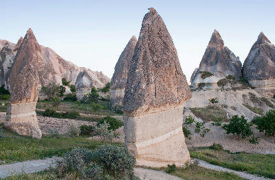 Dark-capped fairy chimneys rising from pale volcanic terrain in White Valley, Cappadocia, Turkey.