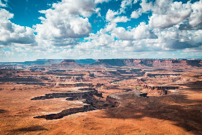 Wide view from Green River Overlook showing river meandering through mesas, cliffs, and layered canyon landscape beneath cloud-filled sky in Canyonlands National Park Utah